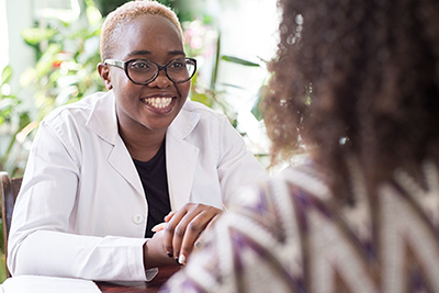 A young African American female doctor with glasses shakes hands with a patient as a sign of trust of a doctor. People of mixed race In the doctors office